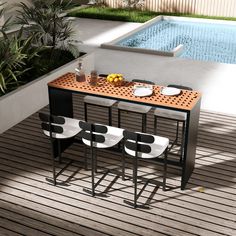 an outdoor dining table with four chairs and plates on it next to a swimming pool