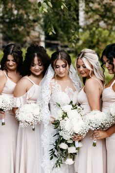 a group of women standing next to each other holding bouquets and wearing bridesmaid dresses