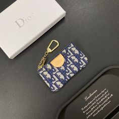 a blue and white wallet with a gold keychain next to it on a table