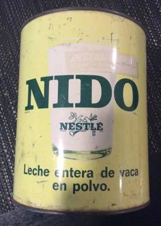 an old yellow tin can with the words nido on it's side, sitting on a black surface