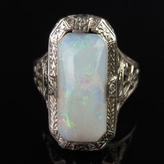 A natural white opal tops this ornate 14k white gold ring by famed jewelers, Ostby & Barton. A carved Art Deco design frames the 13mm x 6mm x 3.8mm cabochon. The white opal has a pinkish undertone with subtle flashes of greens and reds. A pierced filigree design with scrollwork and floral elements decorates the tapered shoulders. The inside of the ring is signed, "OB" (hallmark attributed to Ostby & Barton) followed by "14k" (white gold). The ring measures a petite size 4 (a pinky size for some) White Oval Carved Rings, Art Deco Opal Ring, Zyla Soft Winter, Filigree Ring Gold, Winter Styling, Rms Titanic, Soft Winter, Filigree Design, Floral Elements