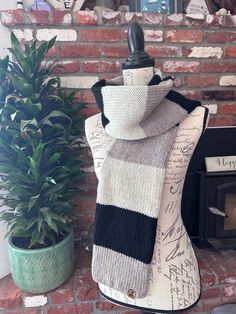 a knitted scarf sitting on top of a mannequin next to a potted plant