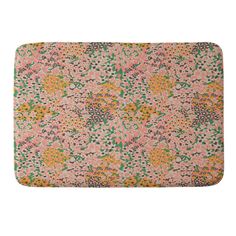 a pink and yellow floral print bath mat with green leaves on the bottom, in front of a white background