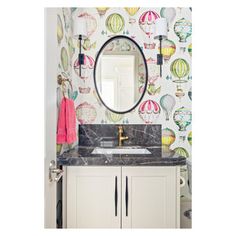 a bathroom with a mirror, sink and wallpapered walls in the background that has hot air balloons on it