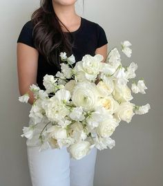 a woman holding a bouquet of white flowers