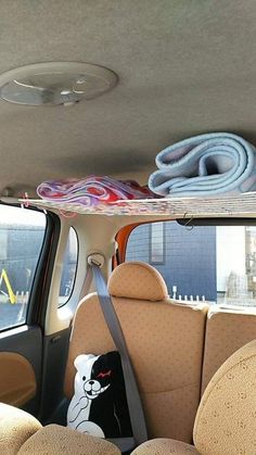 there is a stuffed bear in the back seat of a car with surfboards on top