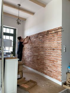 a man is working on a brick wall in the living room and dining room area