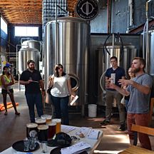 a group of people standing around in a room with beer kegs on the floor