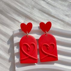 two red heart shaped earrings sitting on top of a white surface