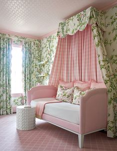 a pink daybed in the corner of a room with floral wallpaper and curtains