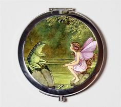 a compact mirror with a fairy sitting on a rock next to a frog and toad