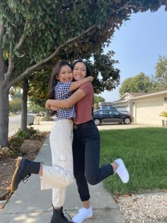 two girls hugging each other on the sidewalk