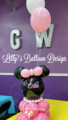 a mickey mouse balloon sculpture on top of a table in front of a purple wall