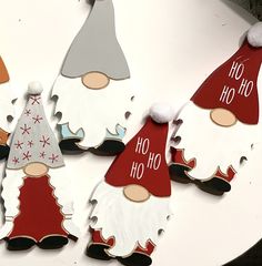 christmas decorations made to look like gnomes on a white table with red and gray hats