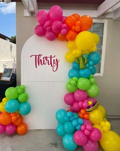 there are many balloons in the shape of a rainbow arch on this birthday party entrance