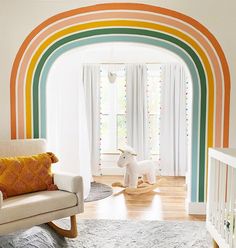 a baby's room with a rocking horse in the center and rainbow painted on the walls