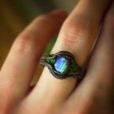 a woman's hand holding a ring with a blue and green stone in it