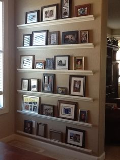 there are many pictures on the wall in this living room, and one is framed with family photos