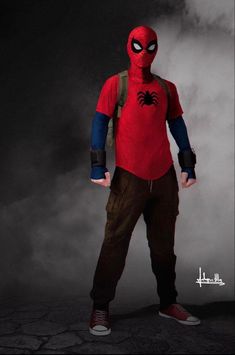 a man dressed as spider - man standing in front of a foggy background with his hands on his hips