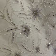 an embroidered fabric with silver flowers and beads on it's center piece is shown