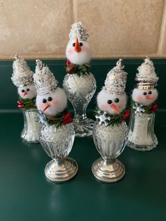 four snowmen are sitting in small glass vases