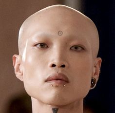 a woman with shaved hair and piercings on her head