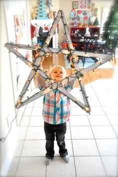 a young boy holding up a star made out of string lights