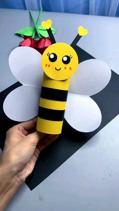 someone is holding up a paper craft bee