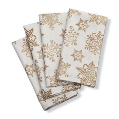 four napkins with gold snowflakes on them