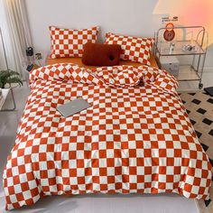 an orange and white checkered comforter set on a bed in a room with black and white flooring