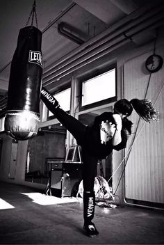 a woman in black shirt kicking a punching bag