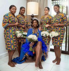 four women dressed in african style clothing posing for a photo with one woman holding flowers