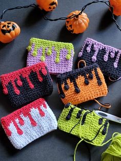 four crocheted purses sitting on top of a table next to yarn and pumpkins