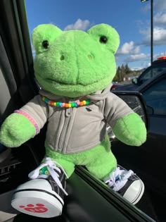 a green stuffed frog sitting in the passenger seat of a car