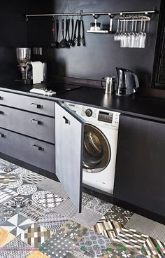 a washer and dryer in a room with black walls, patterned flooring and cabinets