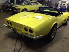 two yellow sports cars in a garage with one being charged by an electric charger