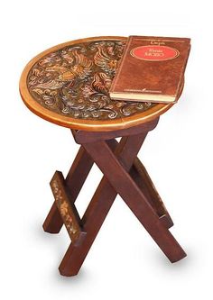 a small wooden table with a book on it's top and a cross leg