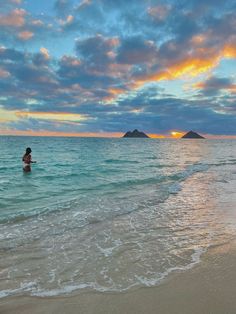 a person in the ocean with an island in the background at sunset or sunrise time