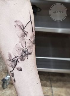 a black and white photo of a woman's leg with orchids on it