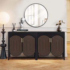 a black and gold sideboard sitting in front of a mirror on top of a wooden floor