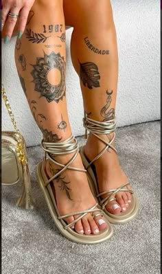 a woman with tattoos on her legs wearing sandals