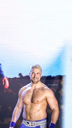 a man with no shirt on standing in front of a crowd wearing boxing gloves and holding his fist up