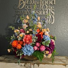 a vase filled with colorful flowers sitting on top of a wooden table next to a metal sign