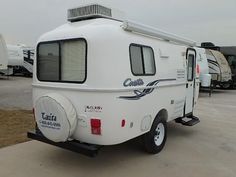 a camper trailer parked in a lot next to other trailers and rvs behind it