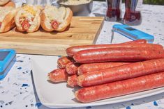 several hot dogs are on a plate next to a cutting board