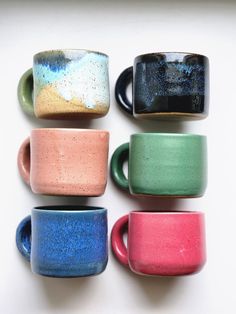 five different colored coffee mugs sitting next to each other