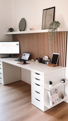 a white desk topped with a computer monitor next to a wooden shelf filled with books