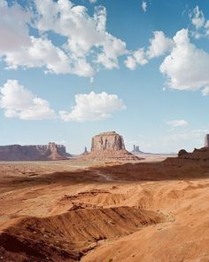 the desert is full of dirt and rocks under a blue sky with clouds in the background