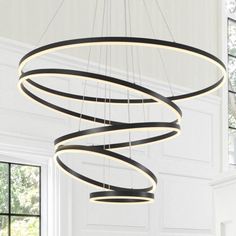 a circular chandelier hanging from the ceiling in a room with white walls and windows