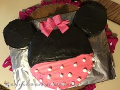 a minnie mouse cake is decorated with pink and black icing on tin foil,